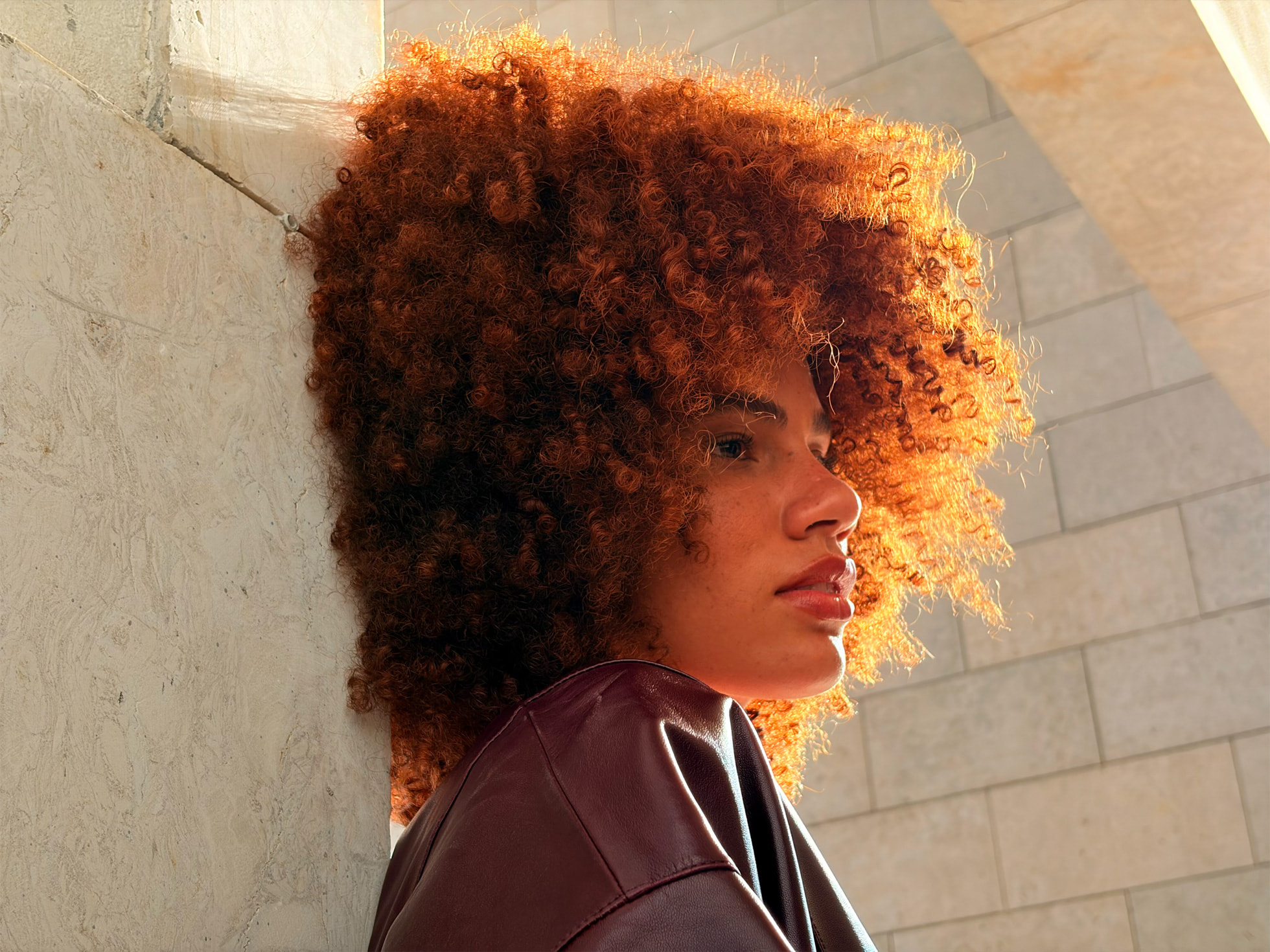 Портрет человека с вьющимися волосами, сделанный на открытом воздухе с помощью 2-кратного телеобъектива на iPhone Air.